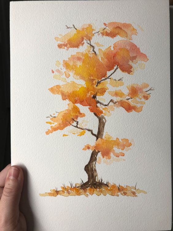 a hand holding a painting of a tree