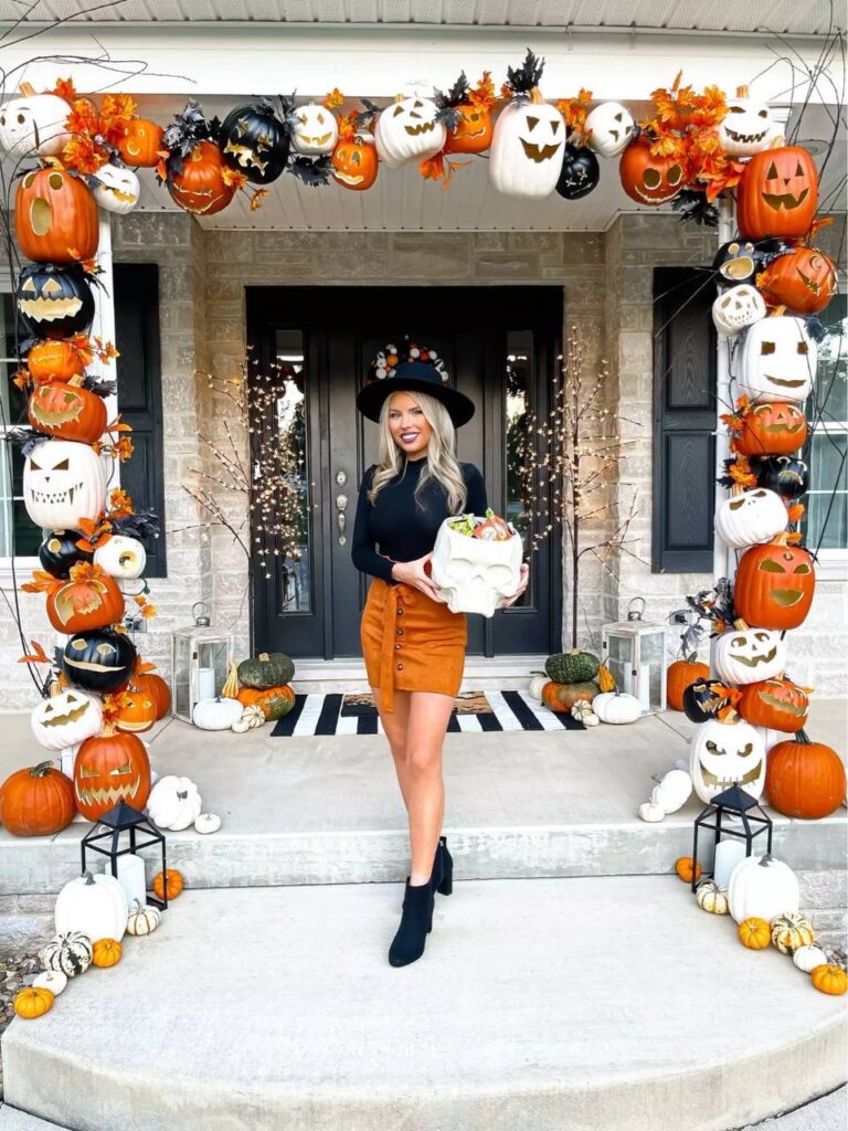 a woman standing in front of a house decorated for halloween