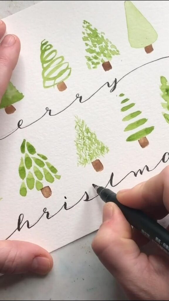 A person is writing merry christmas on a piece of paper.