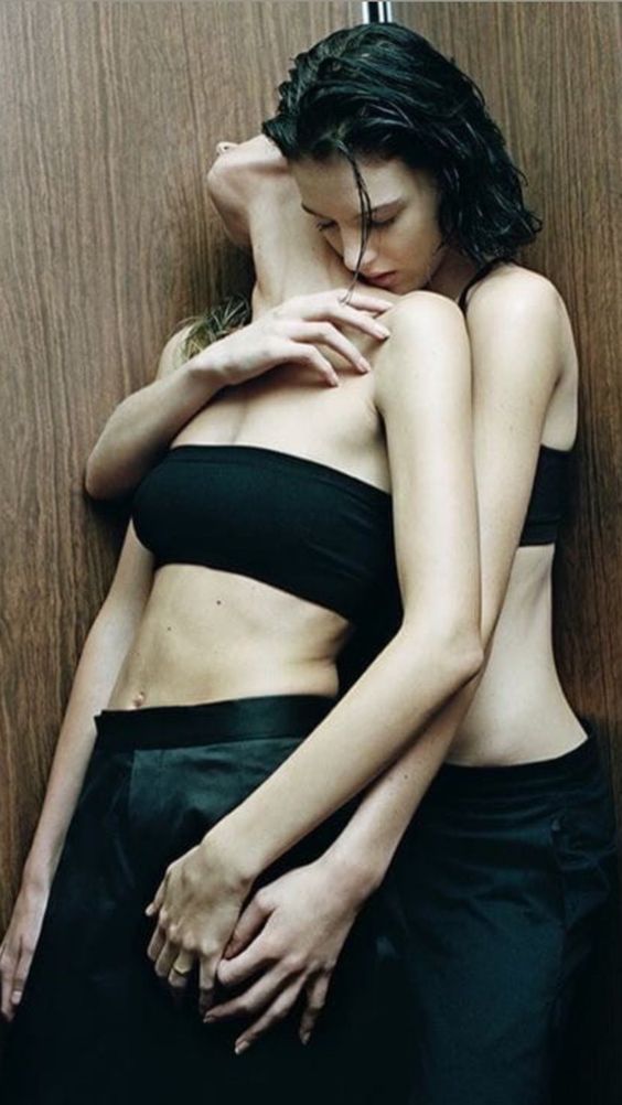 Two women hugging each other in a bathroom.