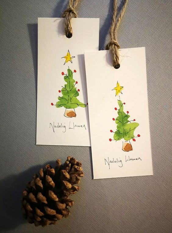 Two christmas tree tags with pine cones next to them.
