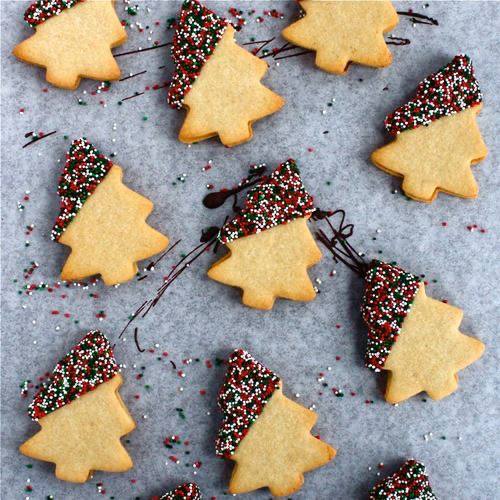 Christmas tree cookies with sprinkles on a baking sheet.