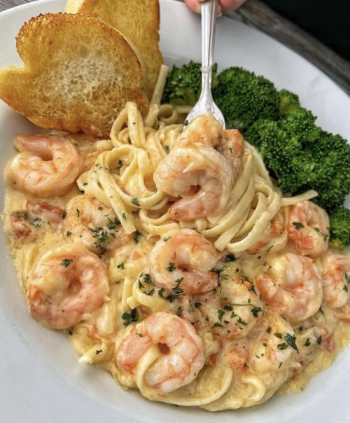 A plate of pasta with shrimp and broccoli.