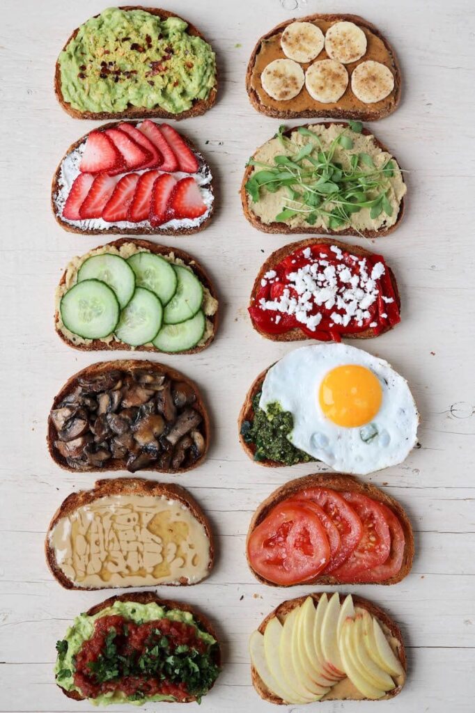 A variety of breakfast toasts are arranged on a wooden surface.