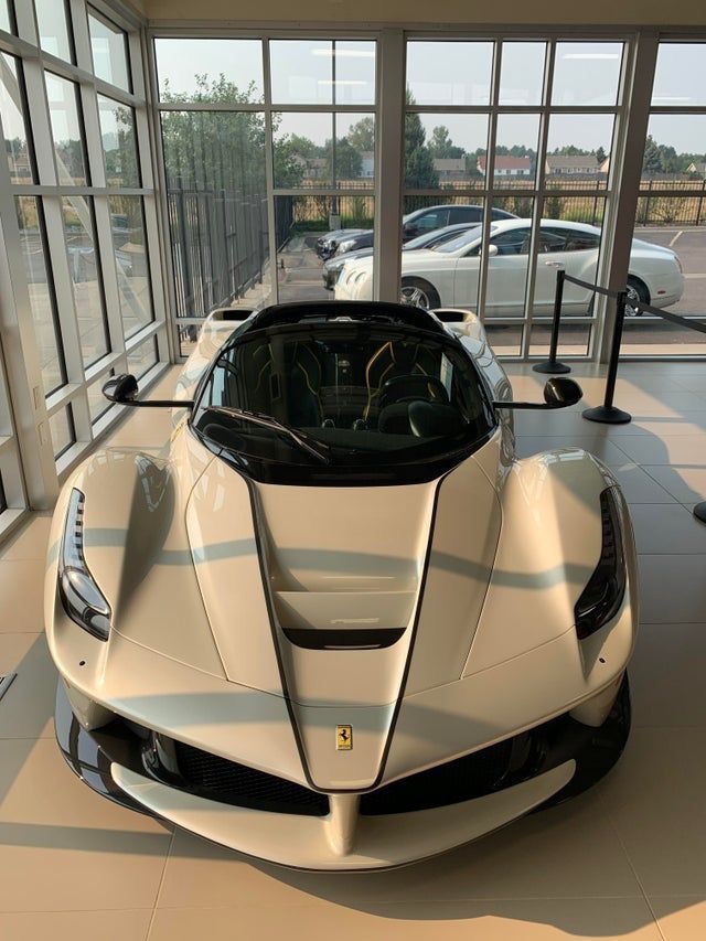 A white sports car is parked in a showroom.