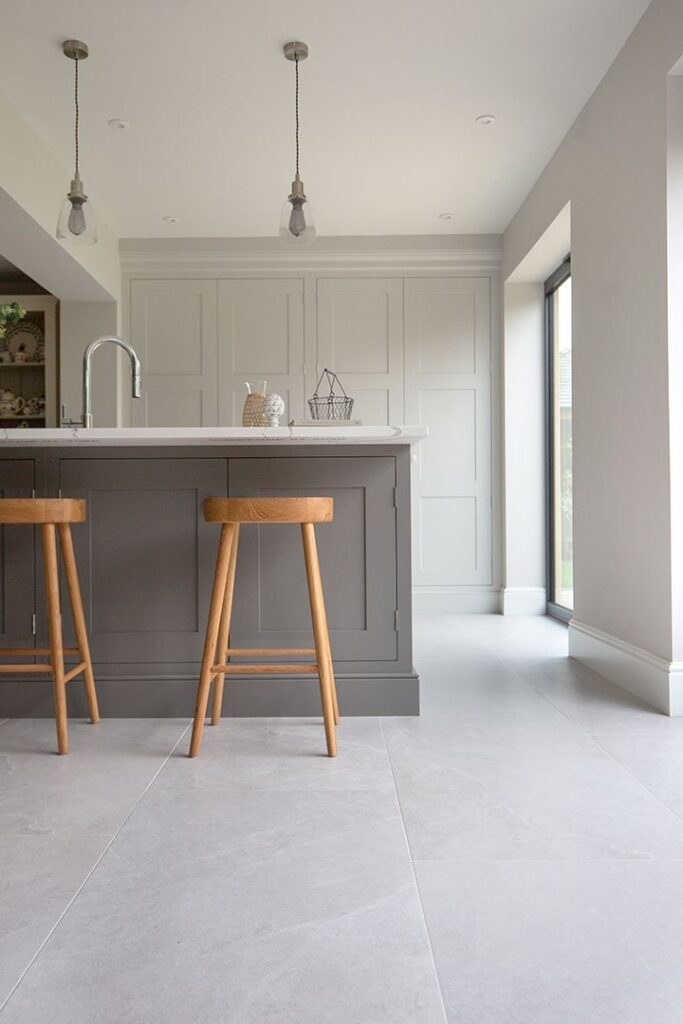 A kitchen with a grey tile floor and stools.