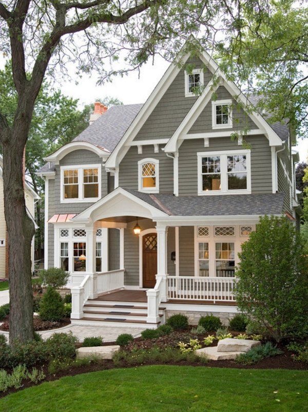 A charming two-story house with a gabled roof, front porch, and landscaped yard.