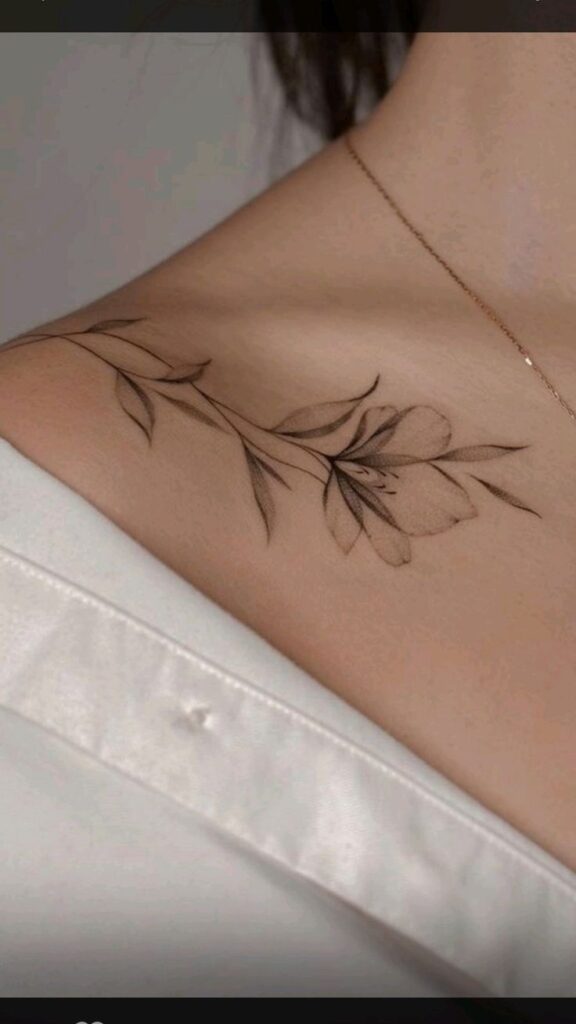 A close-up photo of a woman's side neck showing a delicate floral tattoo.