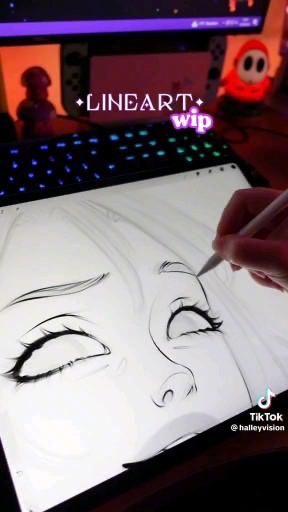 An artist's hand drawing a detailed female face on a digital tablet, with a colorful, illuminated keyboard in the background.