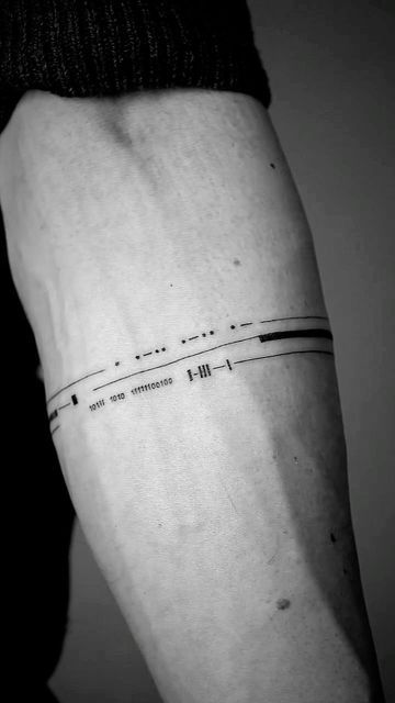 A black and white photo of a forearm with a minimalist barcode tattoo that includes the numbers "1910" and "191019" below it.