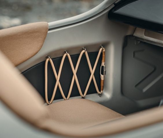 Close-up of a beige elastic net pocket inside a car's trunk, useful for holding small items, featuring a clean, minimalist design.