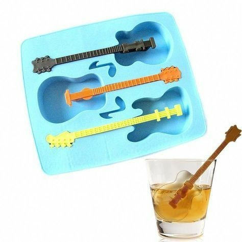 A blue silicone ice tray with guitar-shaped molds beside a glass of whiskey containing ice cubes shaped like guitars.