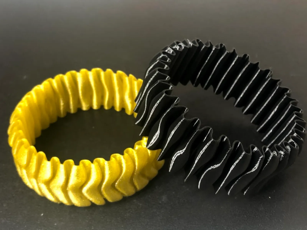 Two coiled phone cords in yellow and black placed side by side on a dark surface.
