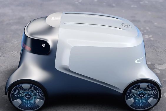 A compact, futuristic robot with a sleek design, black and white body, and blue wheels featuring a prominent circular logo. It appears to be on a flat gray surface.