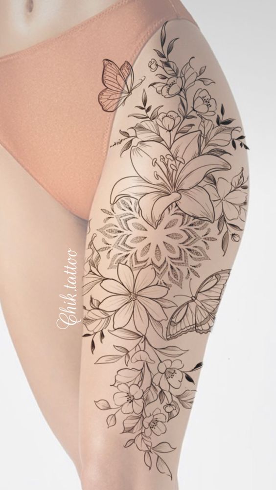 A thigh tattoo featuring intricate flowers, leaves, and butterflies.