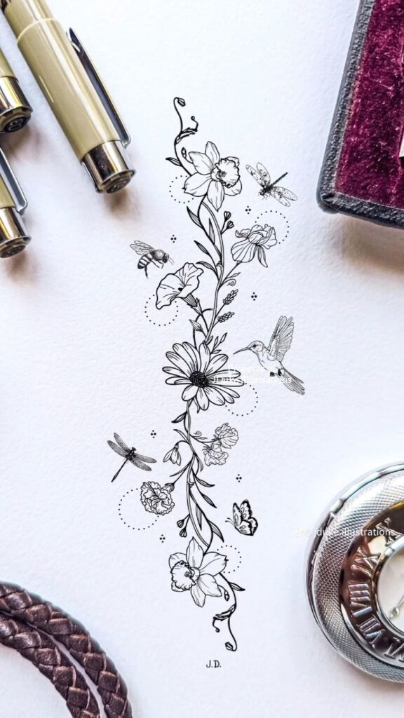 A black ink drawing of flowers, leaves, and birds on white paper, surrounded by pens, a watch, and a woven strap.