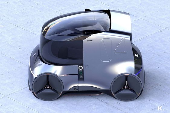 A futuristic, silver, autonomous vehicle with a sleek, rounded design and large circular wheels, seen from an aerial perspective on a light gray tiled surface.