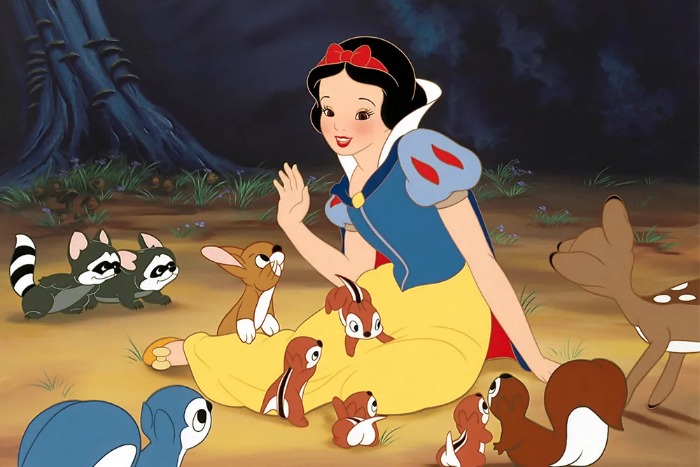 Animated princess in blue-yellow dress sitting with woodland animals including deer, rabbits, raccoons, birds in forest.