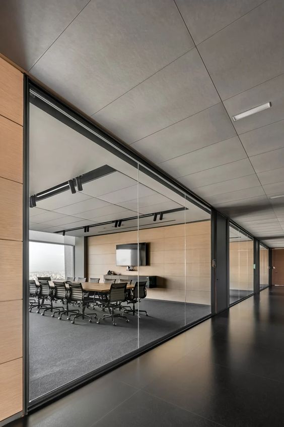 Modern office conference room with glass walls, large table, chairs, and TV screen in minimalist corporate setting.