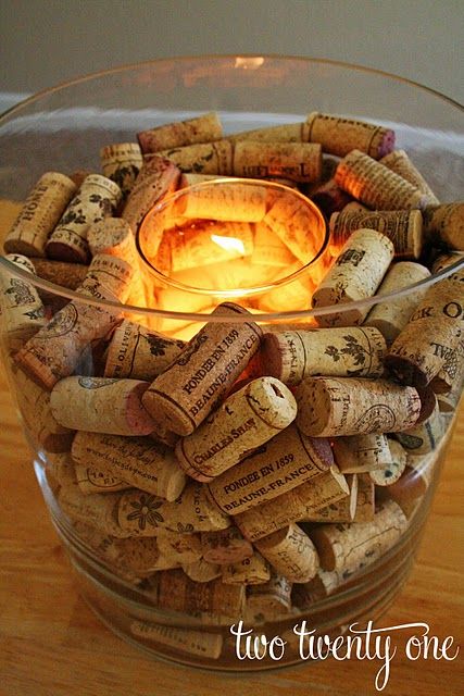 Decorative candle centerpiece surrounded by wine corks in a glass bowl, creating a cozy and warm ambiance.