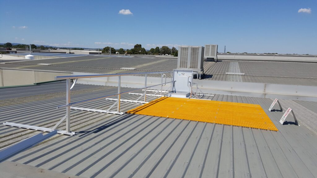 Rooftop safety setup with access platforms and railing for maintenance, featuring clear sky background and industrial setting.