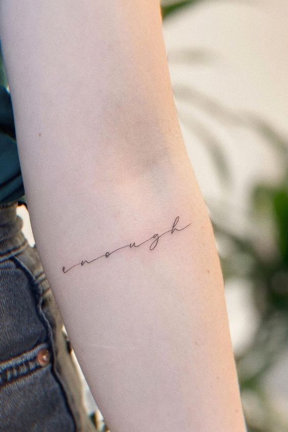 Minimalistic enough script tattoo on inner forearm, symbolizing self-worth and acceptance. Thin, elegant black ink design.