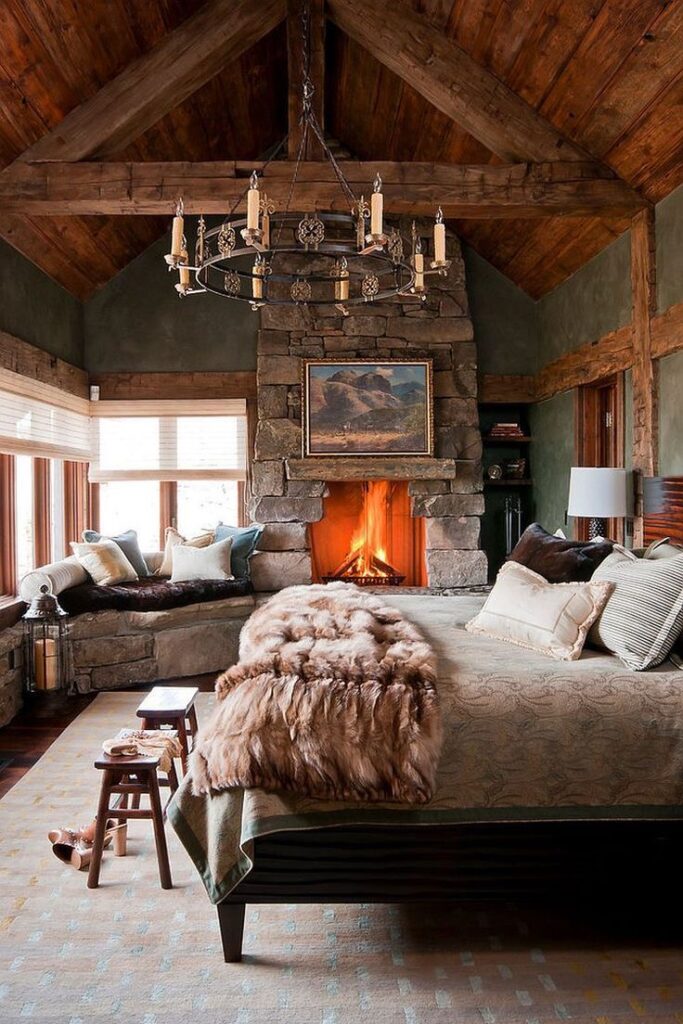Cozy rustic bedroom with stone fireplace, wooden beams, chandelier, and fur blanket on bed for a warm and inviting atmosphere.