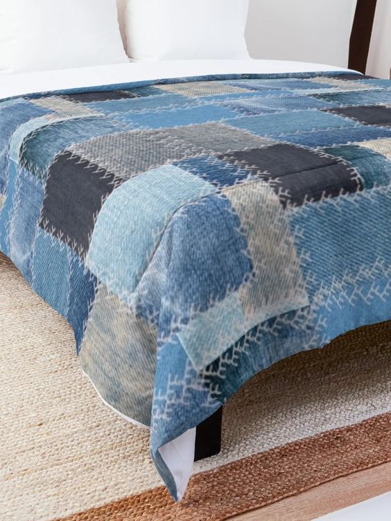 Patchwork denim quilt on a bed with white pillows in a cozy bedroom. Rustic and modern home decor, comforter close-up.