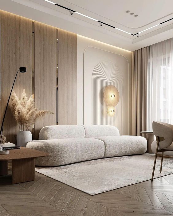 Modern living room with white plush sofa, wooden accent wall, pampas grass decor, and geometric lighting.