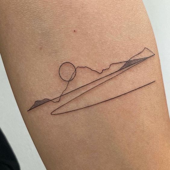 Minimalist tattoo of a mountain landscape with sun and geometric lines on arm, showcasing simple and elegant body art.