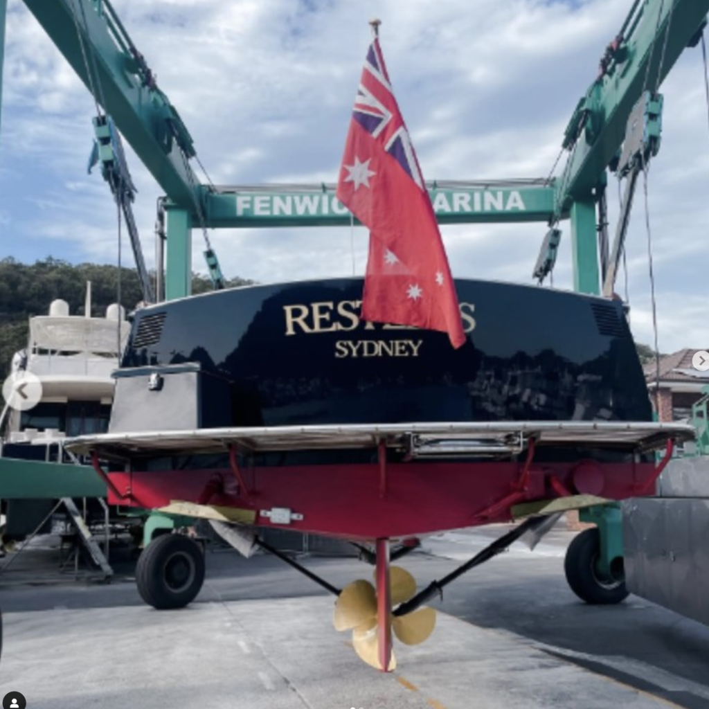 A black yacht named Restless from Sydney getting serviced at Fenwicks Marina, with an Australian flag flying at the stern.