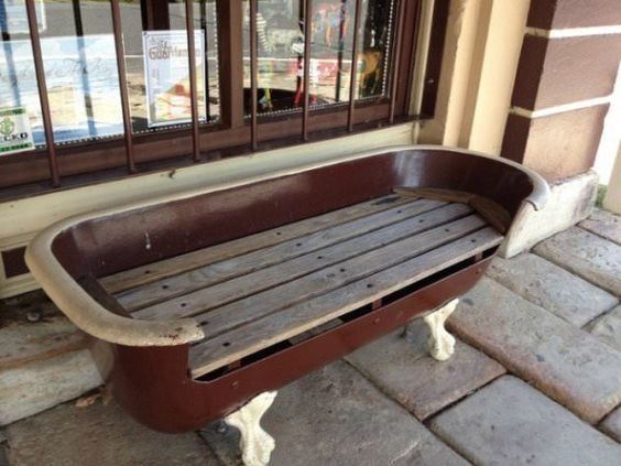 Vintage bathtub repurposed into a rustic outdoor bench in front of a store, adding quirky charm to storefront decor.