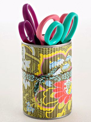 Colorful scissors in a decorated can holder with floral patterns and a ribbon, ideal for an organized and stylish workspace.