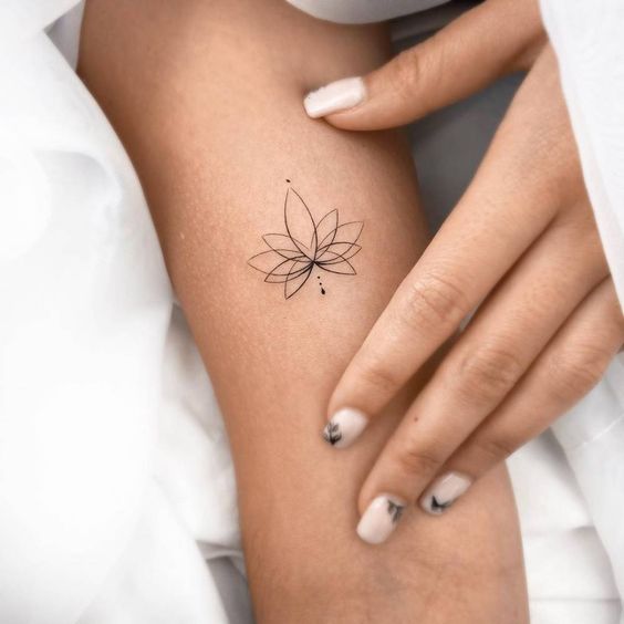 Minimalist geometric flower tattoo on forearm with matching manicured nails, showcasing elegant and delicate body art.