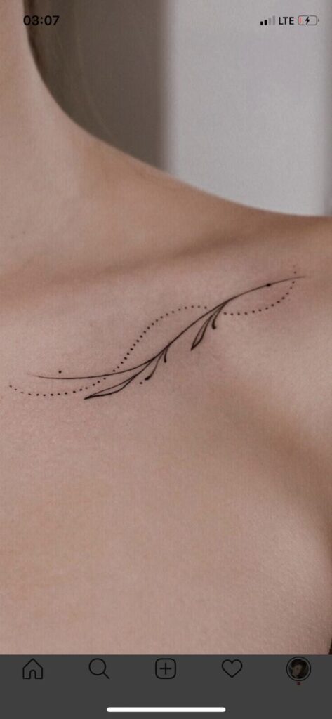Minimalist branch tattoo design on collarbone with dotted lines and small leaves. Modern and delicate body art concept.