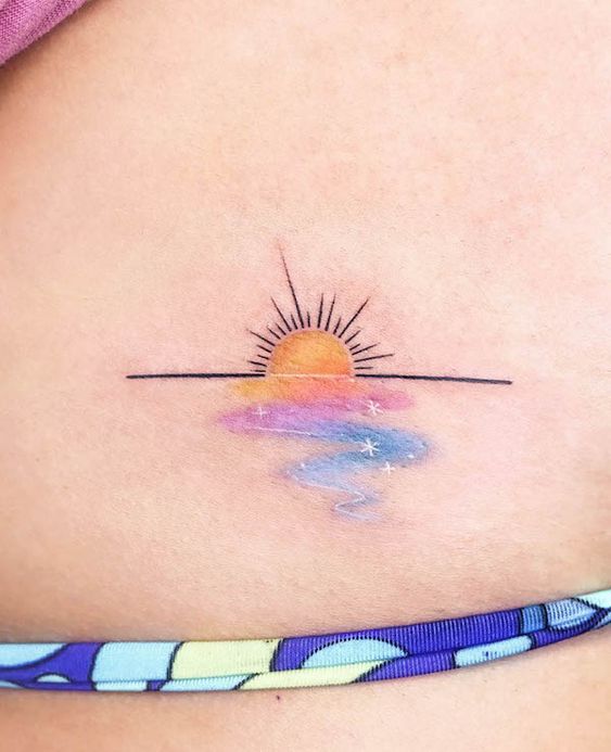 Minimalist sunset tattoo with vibrant pastel colors and stars on skin, captured close-up.