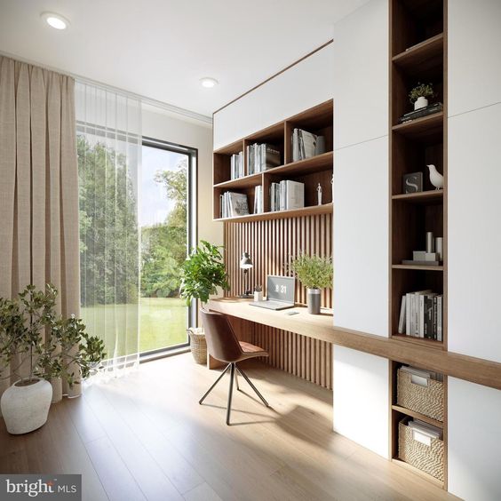 Modern home office with large window, wooden desk, built-in shelves, plants, and natural light; minimalist interior design.