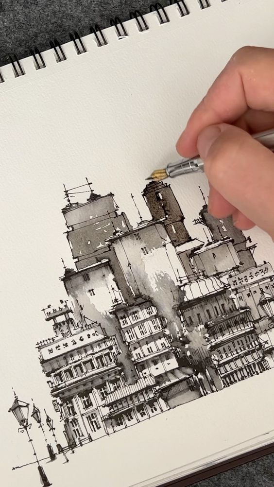 Hand sketching an intricate cityscape in monochrome on a spiral-bound sketchbook with a fine-tip pen.