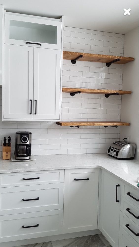 Modern white kitchen with open wooden shelves, white cabinets, countertop appliances, and a subway tile backsplash.