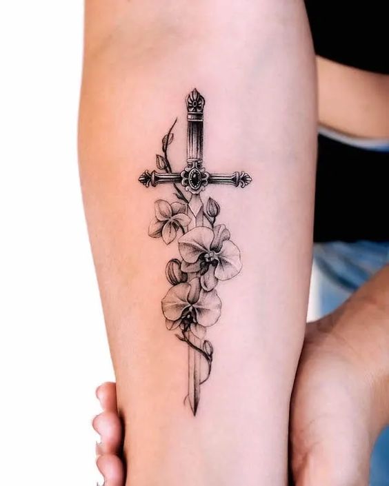 Forearm tattoo with intricate cross and blooming flowers, showcasing fine linework and detailed shading.