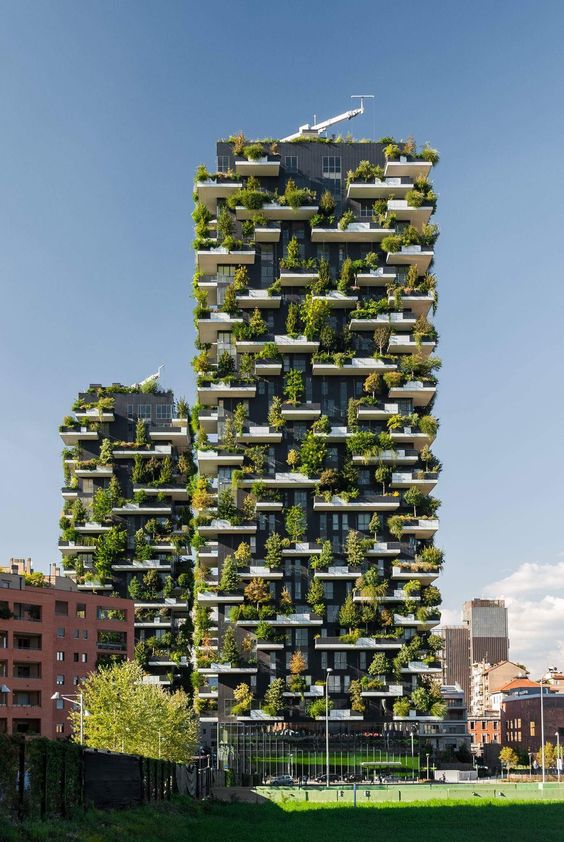 Vertical forest skyscrapers with lush greenery on balconies under the blue sky, showcasing sustainable urban architecture.