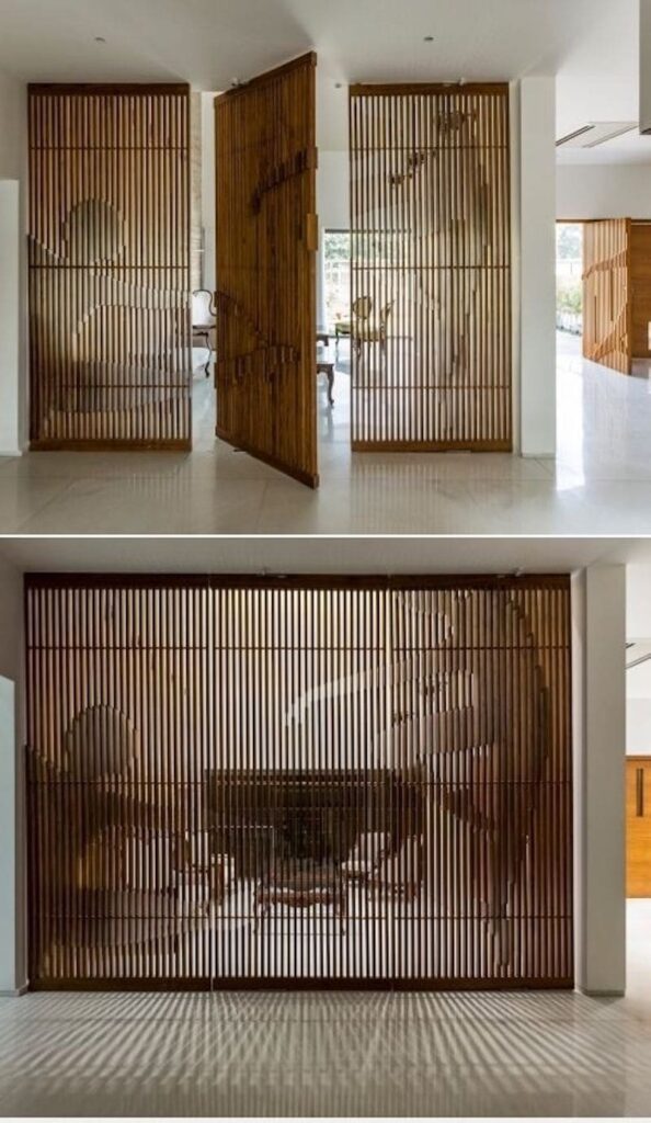 Modern wooden slatted room divider with artistic cutouts in a contemporary living space, casting intricate shadows.