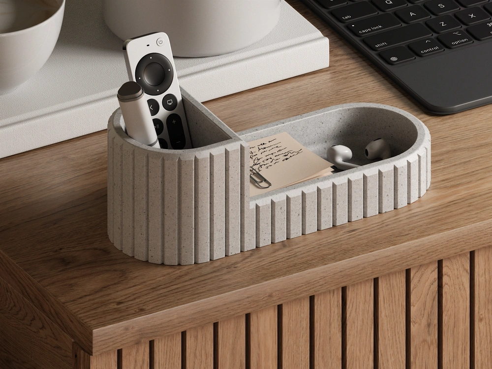 Modern desk organizer with remote controls, note, and AirPods on a wooden table next to a keyboard, enhancing workspace neatness.