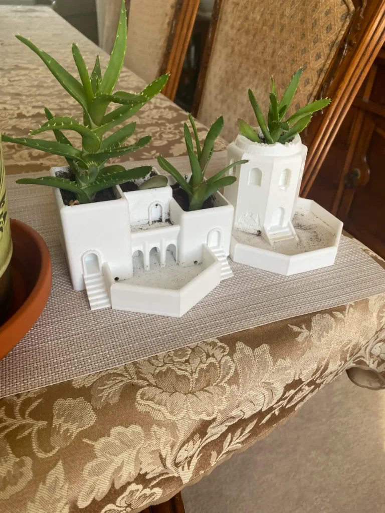 Mini succulent plants in a white architectural planter on a patterned tablecloth, adding greenery to an indoor table setting.