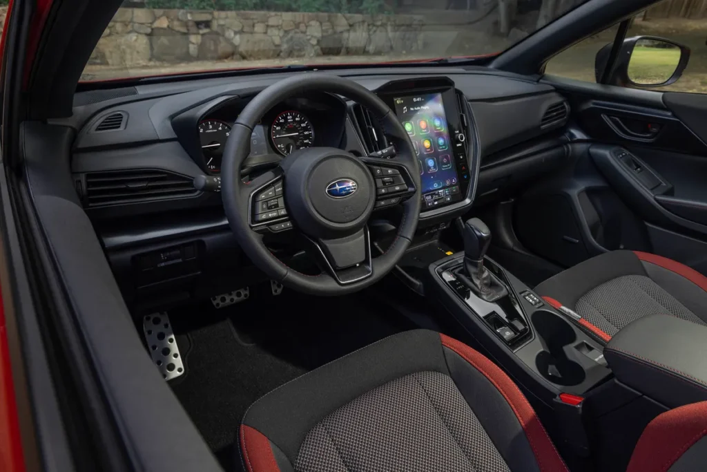 Close-up of a modern car interior featuring a Subaru logo on the steering wheel, digital dashboard, and infotainment system.