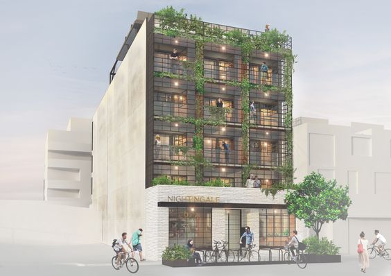 Modern apartment building with green balconies and people in urban setting, outside NIGHTINGALE cafe.