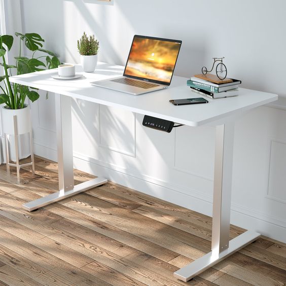 Modern home office with a white standing desk, laptop, and potted plants, providing a bright and ergonomic workspace.