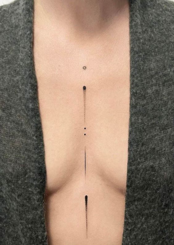 Minimalist geometric chest tattoo with a series of black dots and lines on light skin, underneath a grey garment.