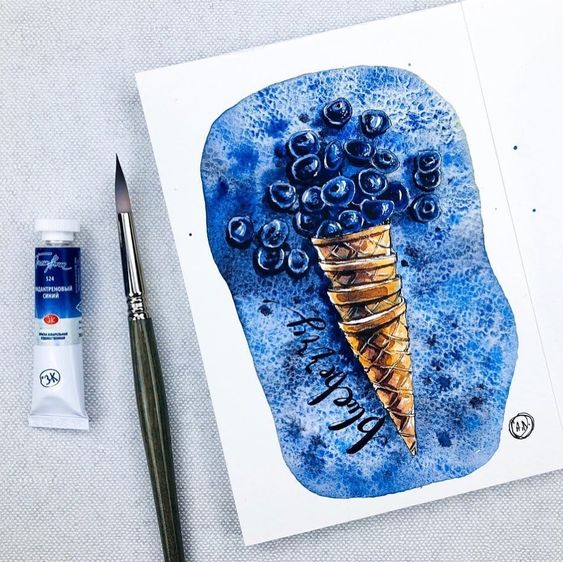 Watercolor painting of blueberries in an ice cream cone with paintbrush and blue paint tube beside it.
