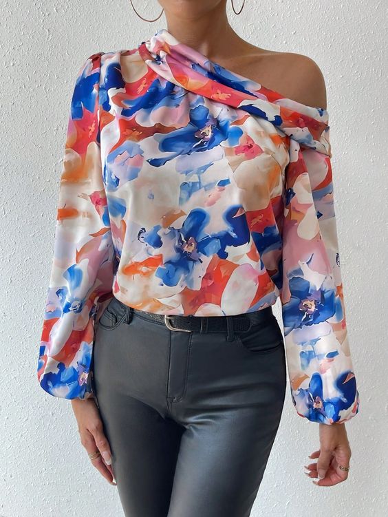 Woman wearing a vibrant floral off-shoulder blouse with long sleeves, paired with high-waisted black pants.